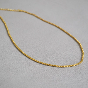 Gros plan d'un collier chaîne corde doré minimaliste avec une texture torsadée