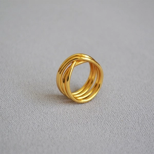 Detail of multi-layer gold plated brass ring with modern intertwined knot design