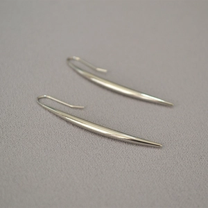 Detailed view of polished silver drop earrings with a sleek minimalist curved design