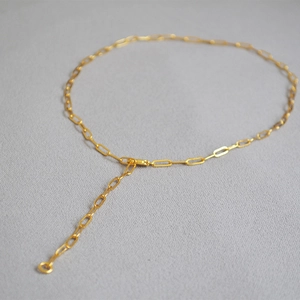 Detail of gold paperclip link necklace featuring adjustable extension chain and circle charm