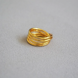 Macro view of multi-layered knotted gold plated brass ring with high-polished finish