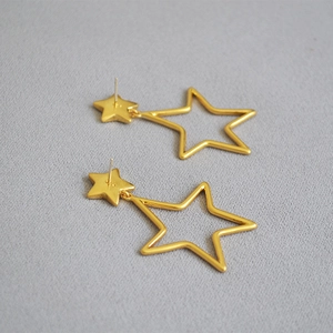 Detail of vintage golden double star dangle earrings with a minimalist cutout design