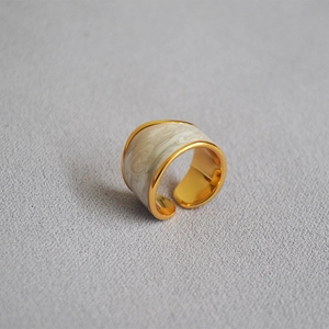 Detailed view of the creamy white marble enamel inlay on a wide gold plated ring band
