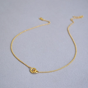 Detail of interlocking double gold rings pendant on a delicate link chain necklace