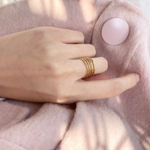 Detail of handmade wire wrapped multi-layer gold ring with pearl and hammer texture