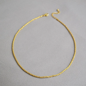 Détail du collier chaîne torsadée dorée avec fermoir mousqueton et chaînette de réglage