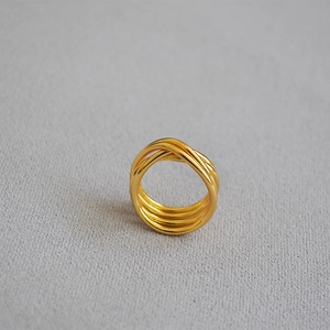 Detailed view of multilayer gold plated brass knotted ring on grey fabric