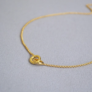 Macro shot of interlocking double ring pendant on delicate gold plated necklace