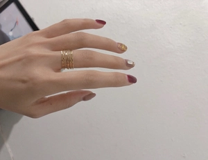 Detail of stacked golden wire rings with hammered texture on a model's hand