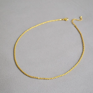 Détail du collier chaîne torsadée dorée montrant le fermoir mousqueton et la chaîne réglable