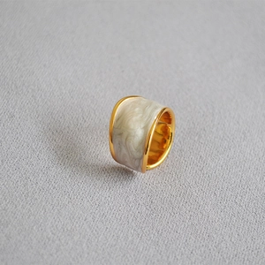 Detail of wide chunky gold ring with white marble enamel inlay and smooth bread-like texture