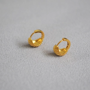 Elegant gold croissant hoop earrings with textured ribbed surface on a grey background