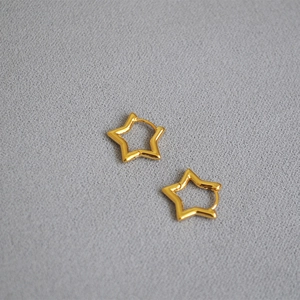 Elegant gold hollow star-shaped hoop earrings on light gray textured fabric