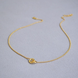 Detailed close-up of double interlocking gold-plated rings on a fine minimalist chain