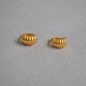 Elegant gold croissant hoop earrings with a textured ribbed surface on a grey background