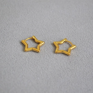 Detail of minimalist gold plated brass star earrings with hollow star design and hoop closure