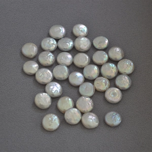 Detailed view of baroque coin pearls with iridescent luster on a dark textured background