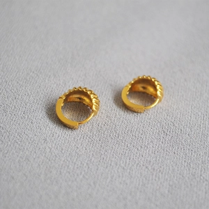 Detail of gold croissant hoop earrings with elegant ribbed texture and clasp closure