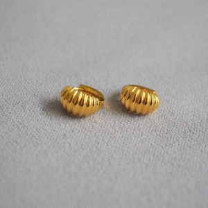 Detail of gold croissant hoop earrings with textured French pleated pattern on gray fabric