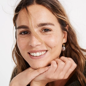 Close-up of French vintage baroque pearl stud earrings worn by a model in soft lighting