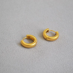 Close-up of golden hoop earrings featuring vertical textured stripes in French style