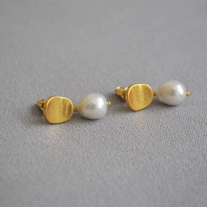 Detailed view of matte gold brass stud earrings featuring irregular baroque pearls