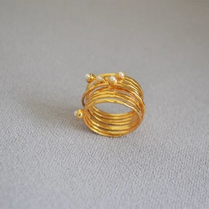 Macro shot of gold wire-wrapped multilayer ring with pearls and hammered texture
