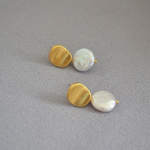 Detailed shot of baroque button pearls with wrinkled gold geometric studs on grey fabric