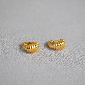 Close-up of golden croissant style hoop earrings with elegant textured ribbed details