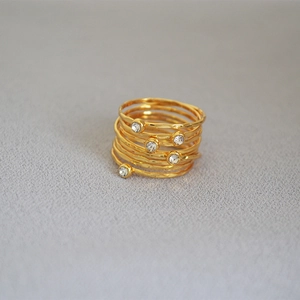 Macro detail of multi-layer gold wire-wrapped ring with hammered texture and crystals