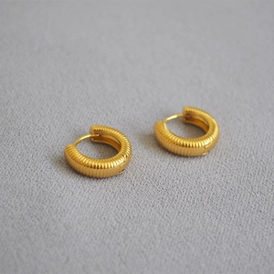 Detail of gold-plated brass hoop earrings featuring a vertical ribbed textured finish