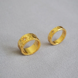 Detail of hammered gold rings with North Star engraving and inset crystal on fabric