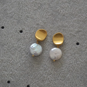 Baroque pearl drop earrings with wrinkled gold studs on grey felt surface