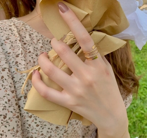 Close-up of golden multi-layered spiral ring worn on model finger in natural sunlight
