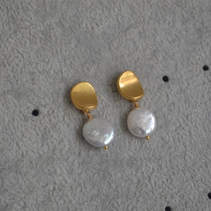 Macro detail of vintage baroque freshwater pearl earrings with matte gold textured studs