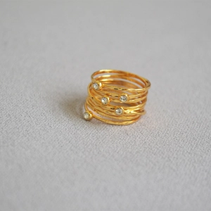 Macro detail of layered gold-plated wire-wrapped ring with hammer texture and crystals