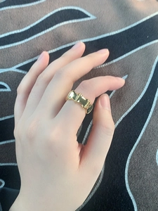 Detailed view of wide gold-plated chain-link ring with polished glossy finish on finger