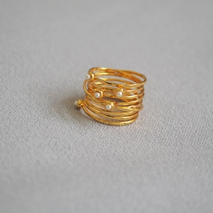 Detailed shot of golden wire-wrapped multi-layer ring with pearls and hammered texture