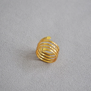 Macro shot of minimalist gold multilayer spiral ring on a textured grey background
