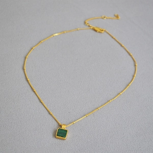 Détail du collier en malachite dorée avec pendentif carré vintage et fermoir mousqueton
