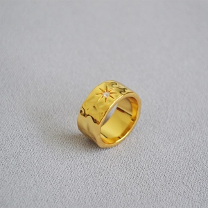 Detail of wide gold ring featuring hammered texture and a North Star zircon engraving