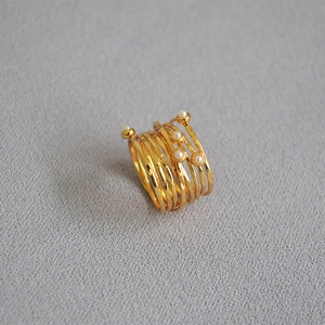 Macro shot of gold layered spiral ring featuring five elegant pearls and textured metal