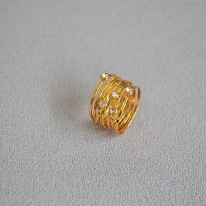 Detail of gold layered wire wrapped ring with clear rhinestones on grey fabric