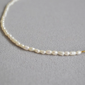Macro shot of white freshwater pearls and golden metal ring on a soft fabric base