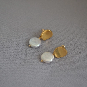 French vintage baroque pearl earrings with golden hammered metal texture on grey fabric