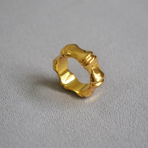 Macro detail of a wide bamboo-shaped gold ring featuring a high-polish mirror finish