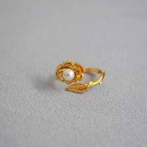 Detail of vintage gold rose ring featuring a white pearl inlay and textured leaf stem