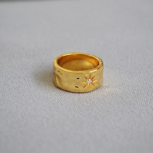 Macro detail of gold-plated brass ring featuring hammered texture and a North Star zircon