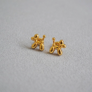 Detail view of golden balloon dog stud earrings featuring a polished metallic finish