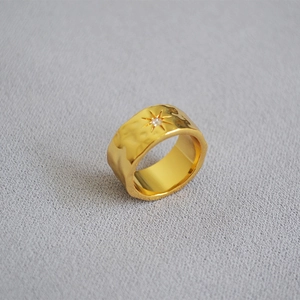 Macro detail of hammered gold plated ring featuring a starburst set cubic zirconia stone